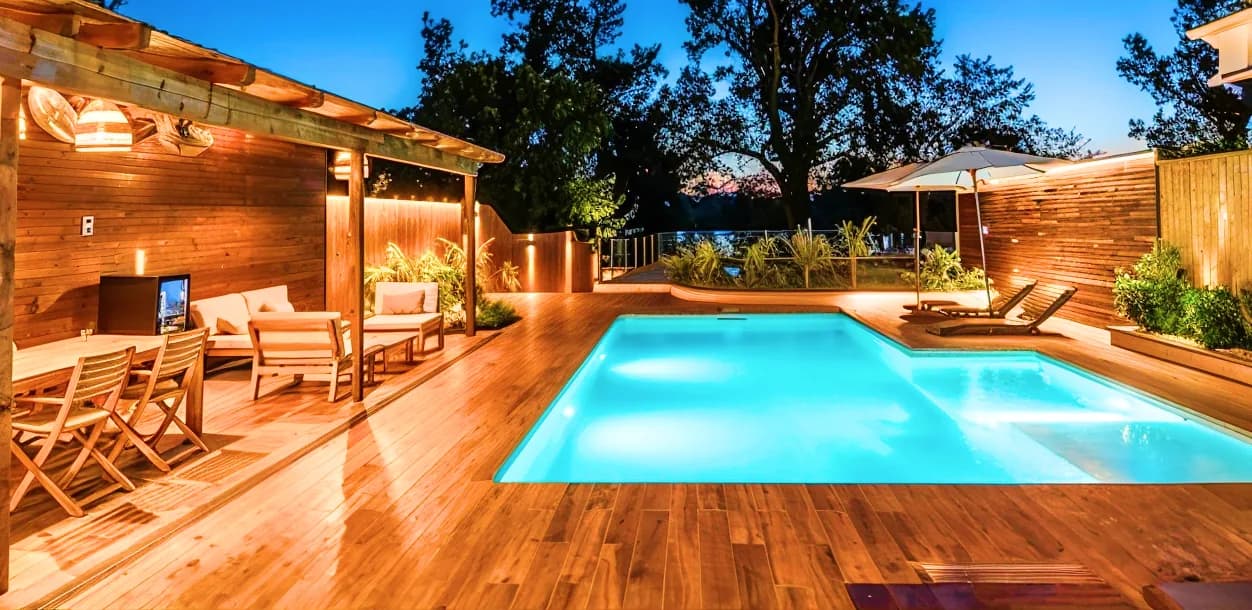 Piscine et terrasse en bois éclairées au crépuscule